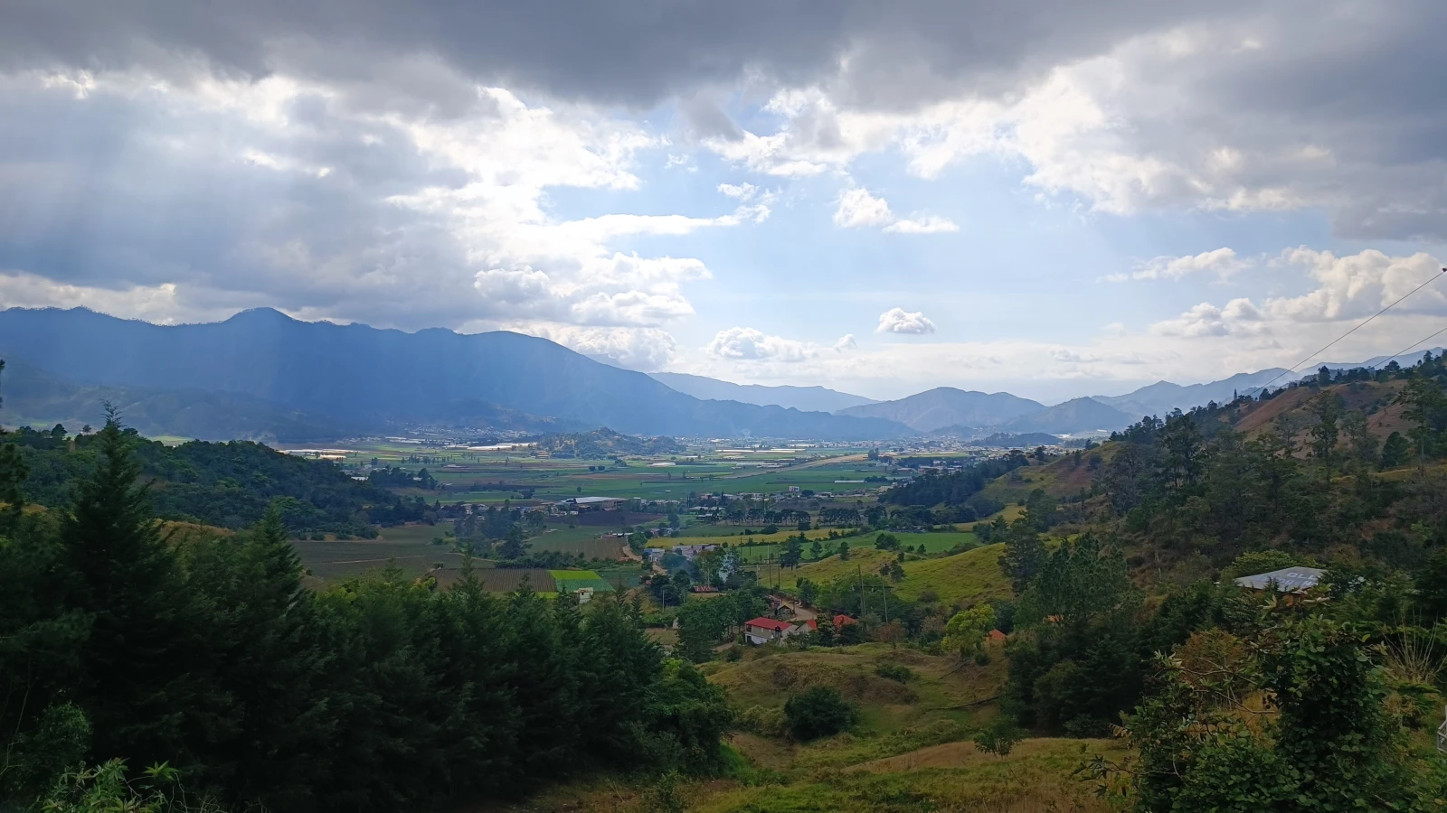 Vista del valle de Constanza con sus cultivos, rodeado de montañas y pinos