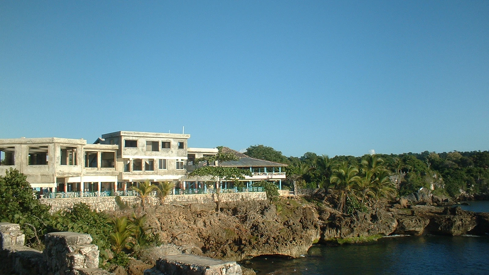 Frente de mar de Boca de Yuma, con casas sobre el acantilado y un cañón antiguo en el malecón