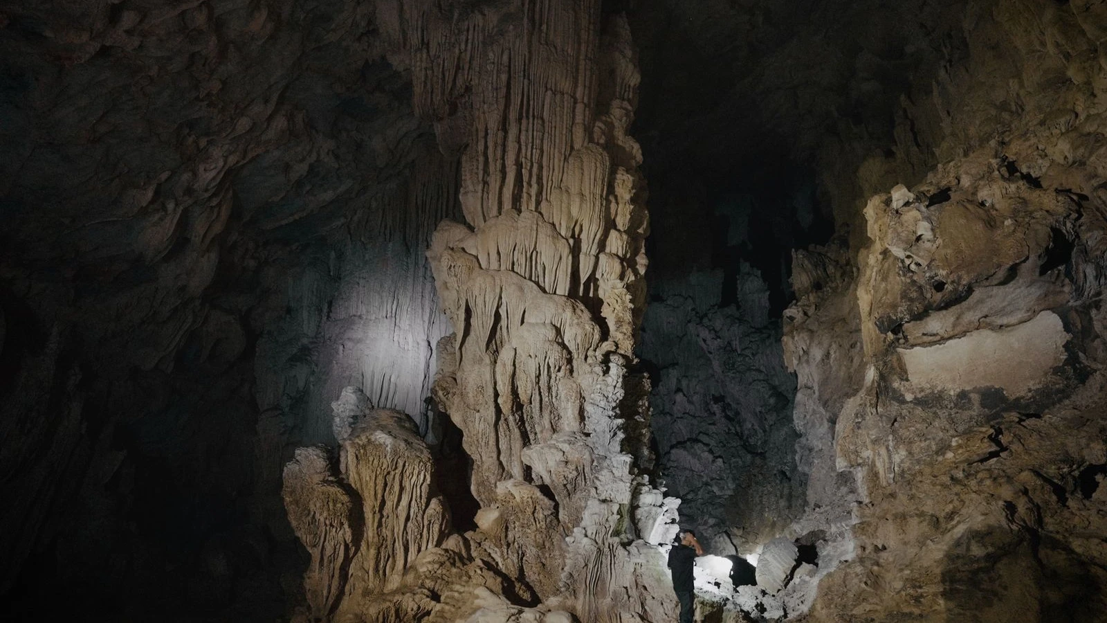 Explorador con luz dentro de una cueva entre estalactitas y estalagmitas