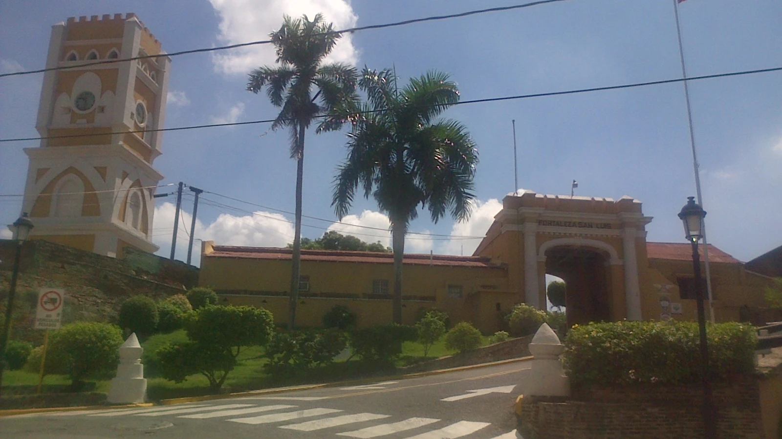 Entrada de la Fortaleza San Luis en Santiago de los Caballeros, con su arco, la torre del reloj, palmas y la bandera dominicana