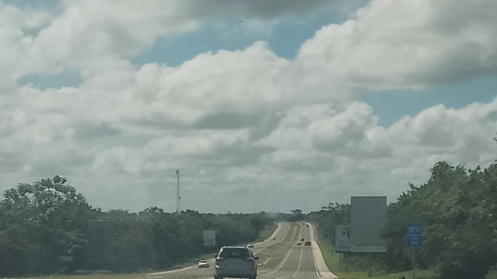 Carros circulando por la Autopista del Coral rumbo a Punta Cana, con una antena de celular al fondo