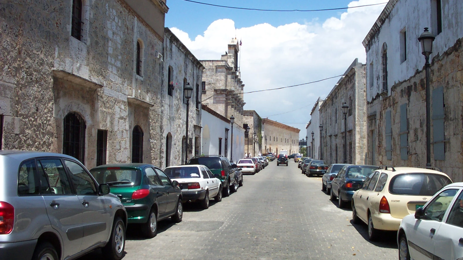 Calle Las Damas en la Zona Colonial de Santo Domingo, con casas coloniales de piedra y carros parqueados