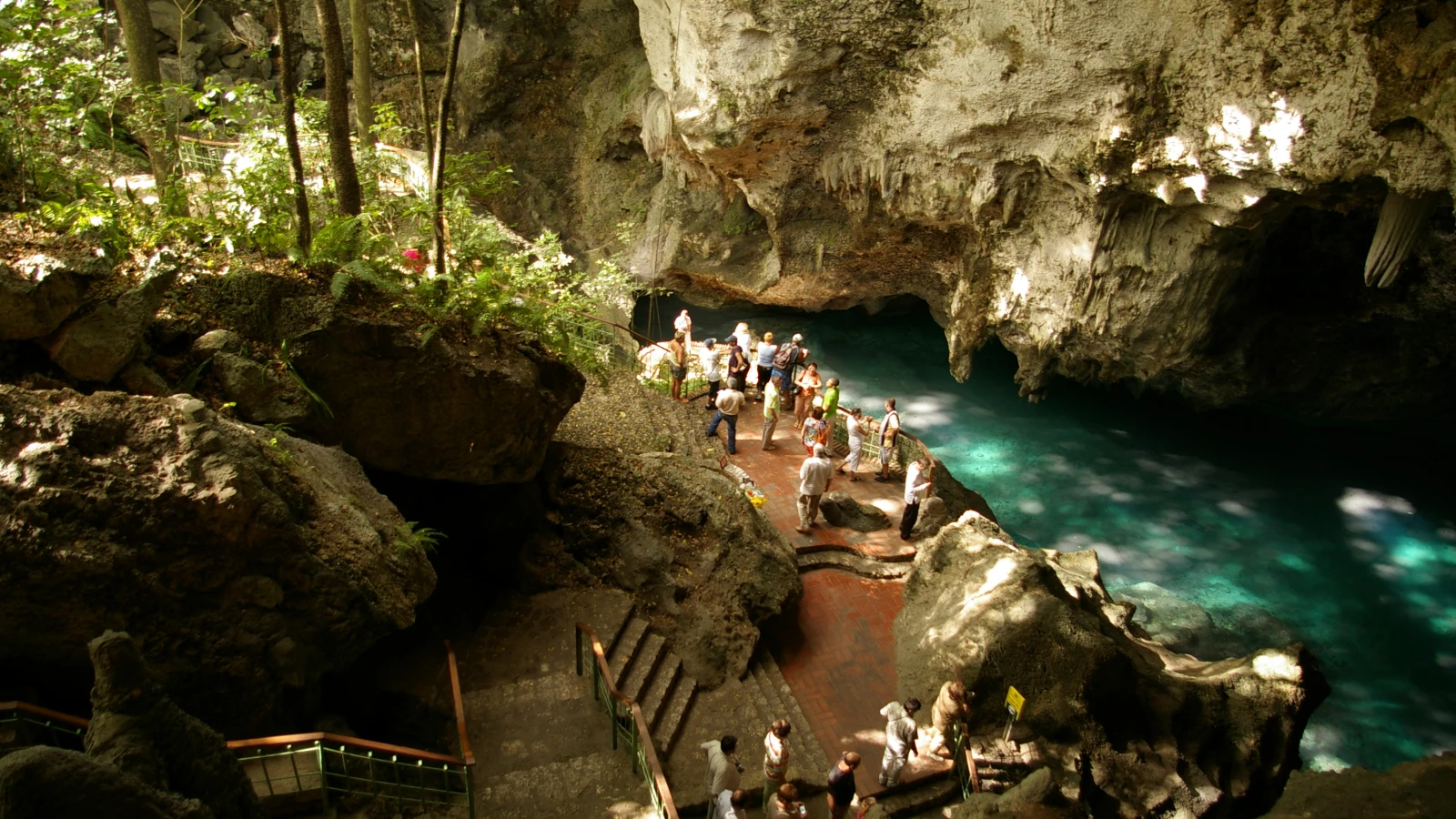 Visitantes junto a uno de los lagos turquesa dentro de la cueva de Los Tres Ojos en Santo Domingo Este