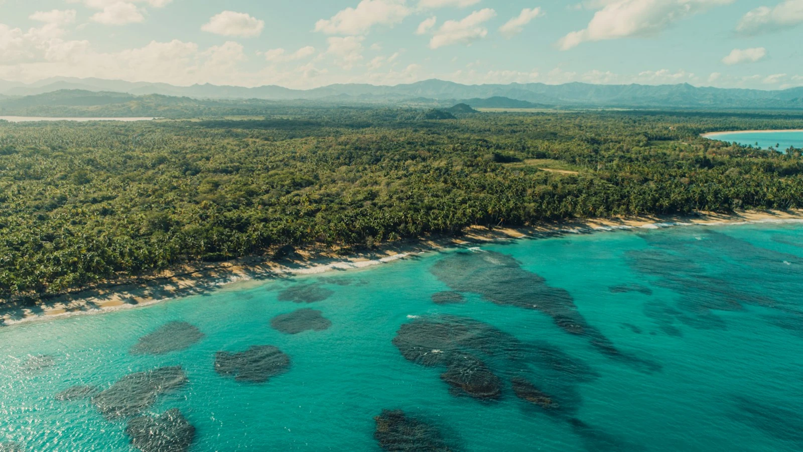 Vista aérea de la costa de Miches, con bosque verde, arena clara y agua turquesa en Playa Esmeralda