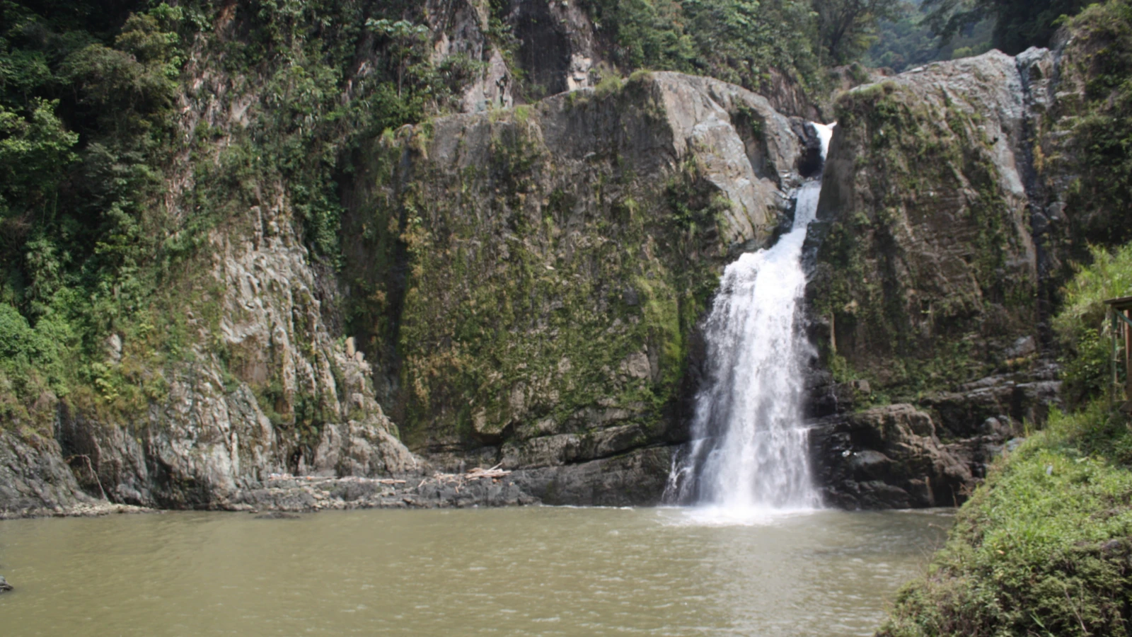 El Salto de Jimenoa cayendo entre rocas y vegetación sobre una poza en Jarabacoa